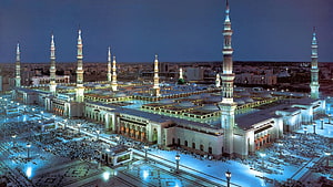 Al-Masjid an-Nabawi in Medina at Night with Illuminated Minarets and Crowded Courtyards HD wallpaper
