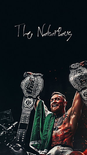 Conor McGregor holding UFC championship belts with Irish flag draped over shoulder HD phone wallpaper