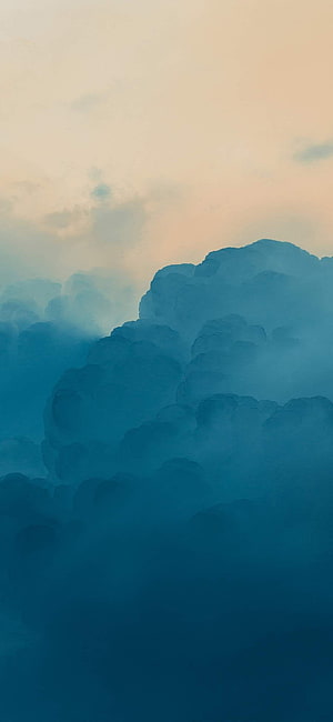 Serene Blue Clouds Against a Soft Peach Sky at Sunset HD phone wallpaper