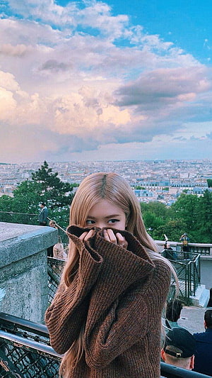 Rose from Blackpink posing in a brown knit sweater with a Paris cityscape background HD phone wallpaper