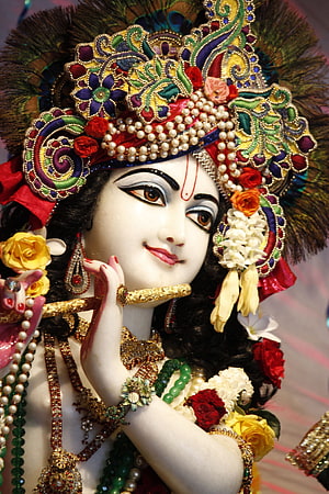 Ornate Krishna Idol Playing Flute with Peacock Feather Crown and Floral Jewelry HD phone wallpaper