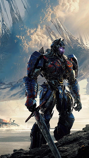 Optimus Prime wielding a sword in a dramatic sci-fi landscape with futuristic ruins and clouds HD phone wallpaper