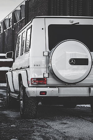 Rear View of White Mercedes-Benz G-Class SUV with Spare Tire and Urban Brick Background HD phone wallpaper