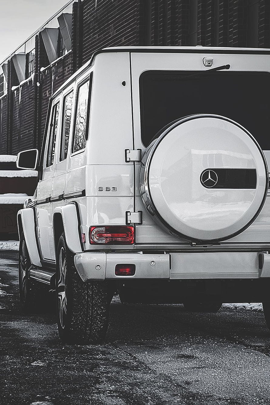 Rear View of White Mercedes-Benz G-Class SUV with Spare Tire and Urban Brick Background HD phone wallpaper