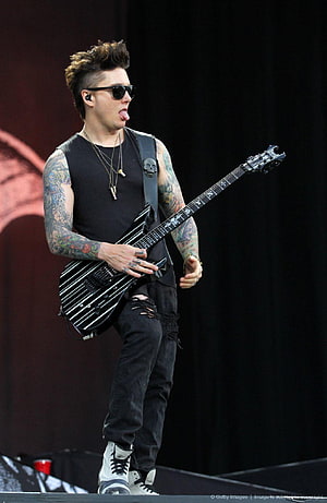 Synyster Gates performing live on stage with electric guitar and tattoos HD phone wallpaper