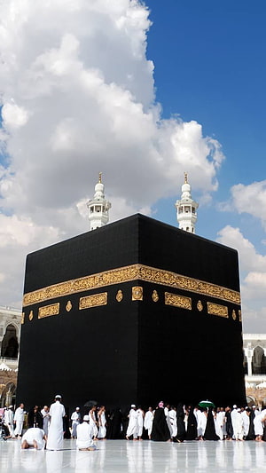The Sacred Kaaba in Makkah with Pilgrims Performing Tawaf Under a Bright Blue Sky HD phone wallpaper