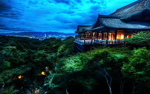 Traditional Japanese Pavilion Overlooking a City at Dusk with Lush Forest and Dramatic Blue Sky HD wallpaper