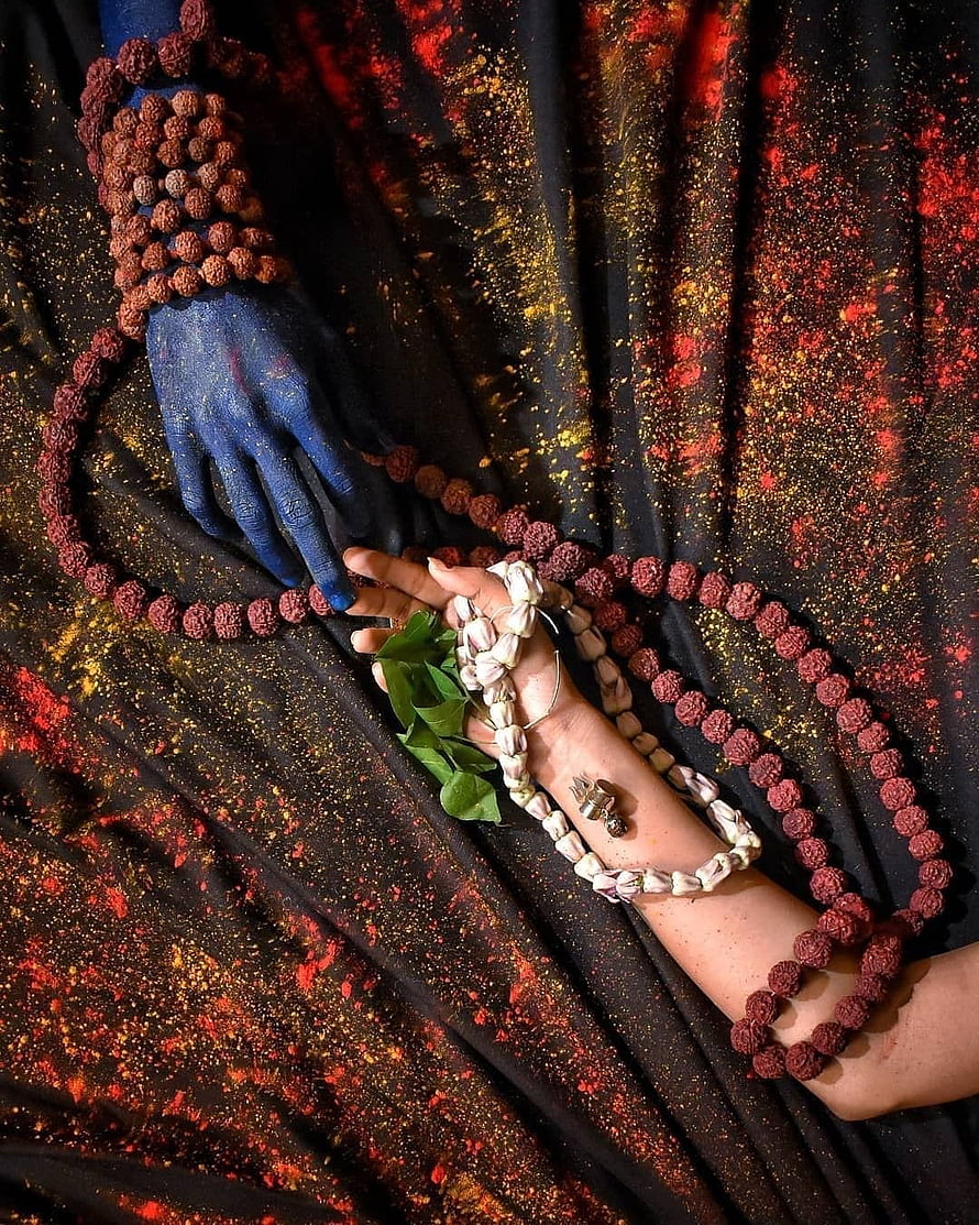 Blue Painted Hand Holding Rudraksha Mala and Tulsi Leaves on Black Cloth HD phone wallpaper