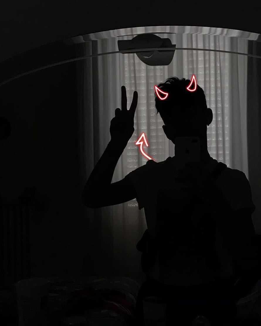 Silhouette of a person with glowing red devil horns and a peace sign in a dark room HD phone wallpaper