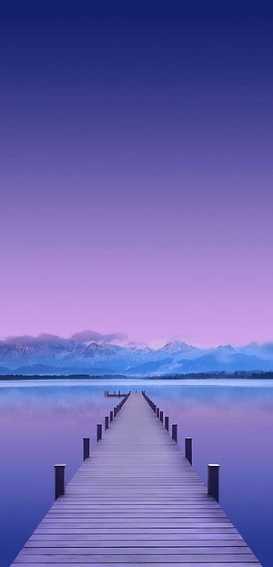 Serene Wooden Pier Extending Into Calm Lake With Purple Sky And Distant Mountains HD phone wallpaper