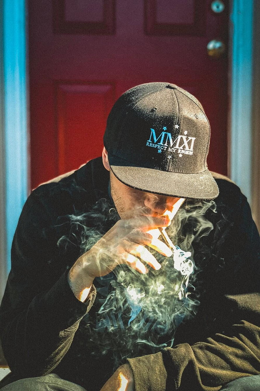 Man in Black Cap Smoking Cigarette with Billowing Smoke Against Red Door, Sad Smoker Boy, mood off boy HD phone wallpaper