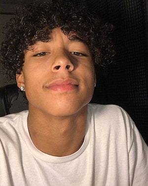 Close-up portrait of a young man with tight dark curls and a white t-shirt, Cute Dark Skin Boys posted by Sarah Tremblay, curly hair light skin boy HD phone wallpaper