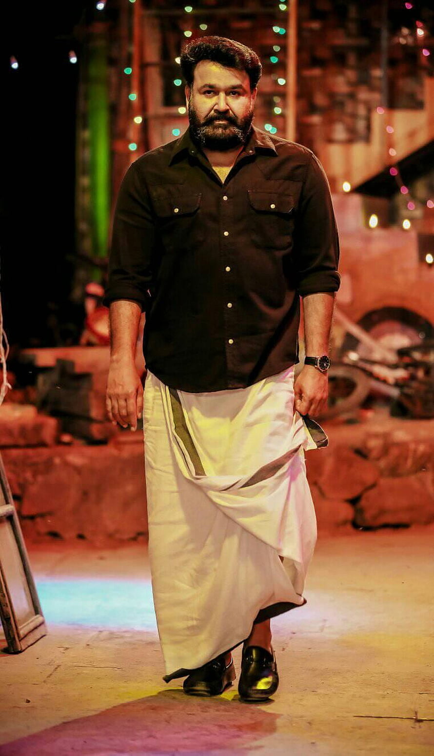 Mohanlal as Lucifer in traditional white dhoti and black shirt on a cinematic stage set HD phone wallpaper