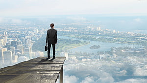 Businessman in a suit standing on a wooden platform overlooking a sprawling city skyline, Business Success, successful man HD wallpaper