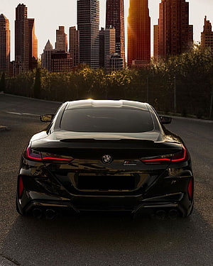 Rear View of Black BMW M8 Competition on City Road at Sunset HD phone wallpaper