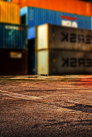 Low Angle View of Textured Asphalt with Blurred Shipping Containers in Background HD phone wallpaper
