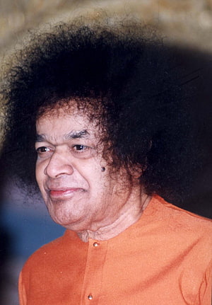 Portrait of Sathya Sai Baba in an orange kurta with a gentle expression HD phone wallpaper