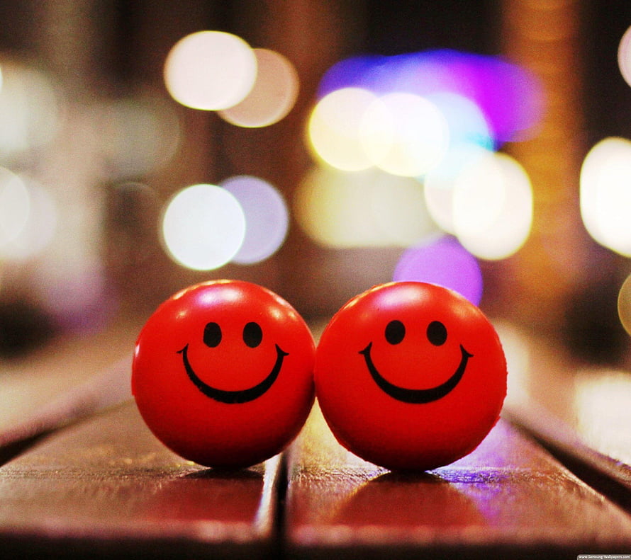 Two Red Smileys Sitting Together on Wooden Planks with Bokeh Lights HD wallpaper