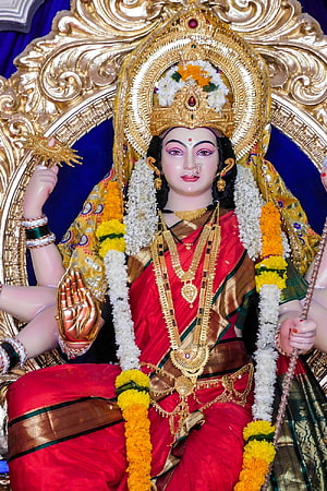 Goddess Durga Statue in Red Saree with Golden Jewelry and Floral Garlands HD phone wallpaper