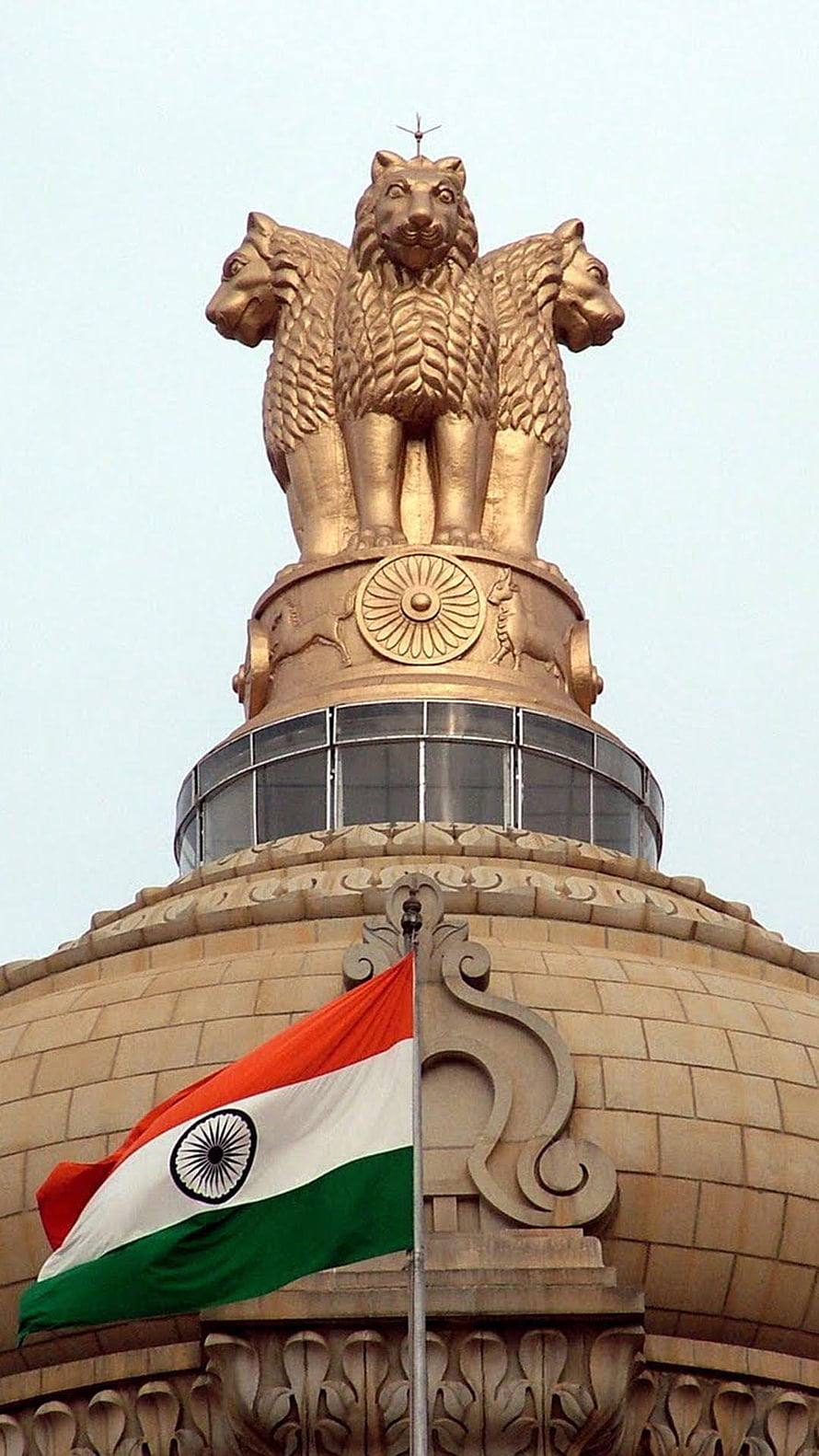 Golden Lion Capital of Ashoka atop the Indian Parliament House dome with the national flag waving in the foreground HD phone wallpaper