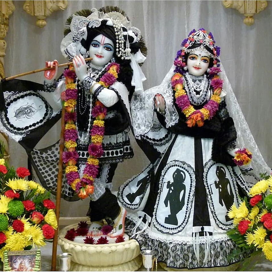 Radha Krishna idols dressed in black and white traditional attire with floral garlands HD phone wallpaper