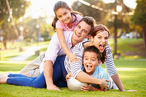 Smiling Family Pile On Grass With Soccer Ball In Sunny Park HD wallpaper