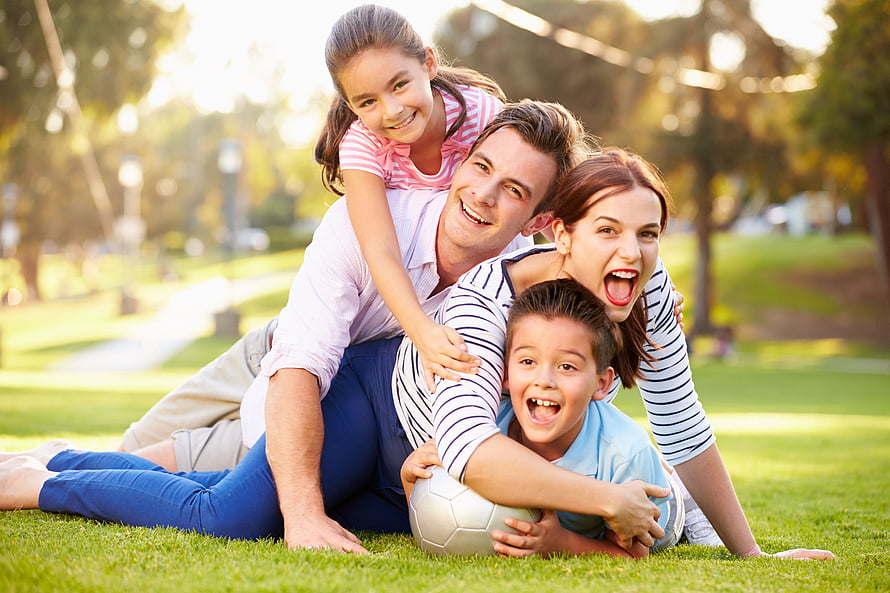 Smiling Family Pile On Grass With Soccer Ball In Sunny Park HD wallpaper