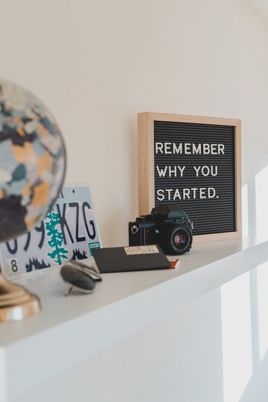Minimalist desk setup with vintage camera, globe, and motivational letter board quote HD phone wallpaper