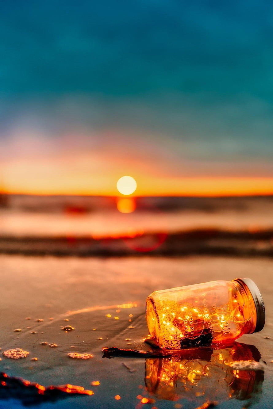 Glowing Jar of Fairy Lights on Wet Sand at Sunset Beach HD phone wallpaper