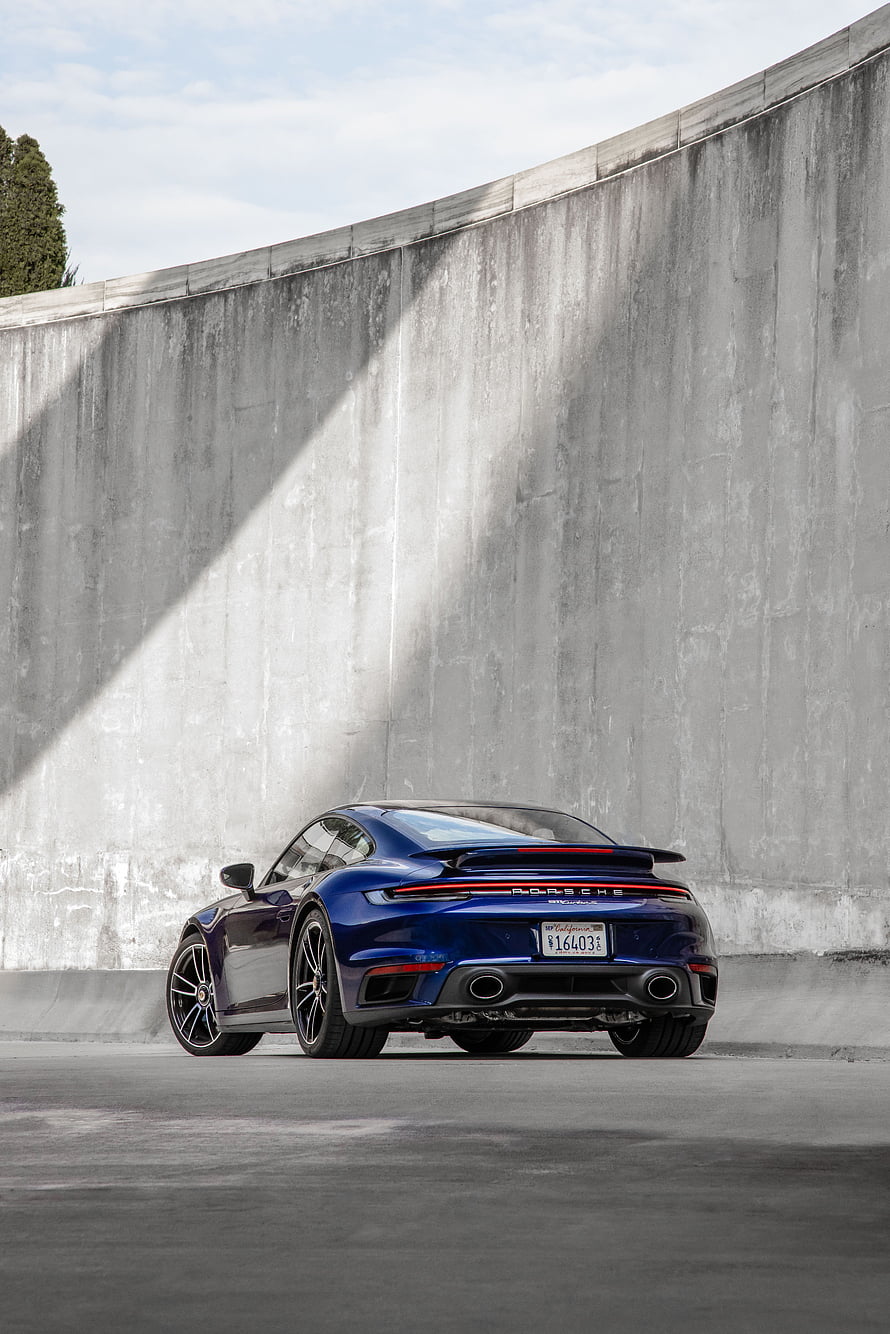 Rear Three-Quarter View of a Blue Porsche 911 Turbo S Coupe Parked Against a Concrete Wall HD phone wallpaper