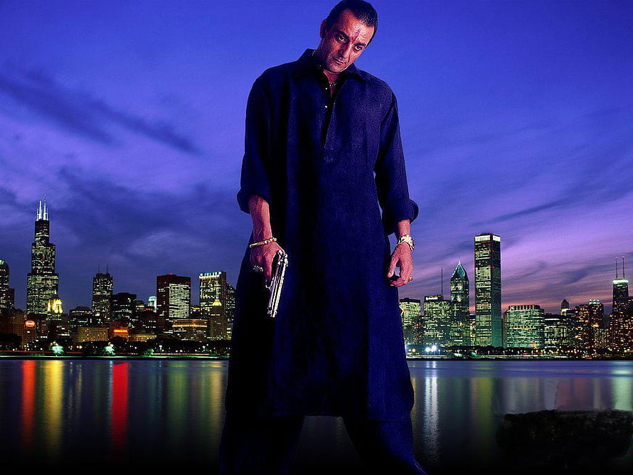 Sanjay Dutt in a dark robe holding a pistol against a Chicago skyline at dusk HD wallpaper