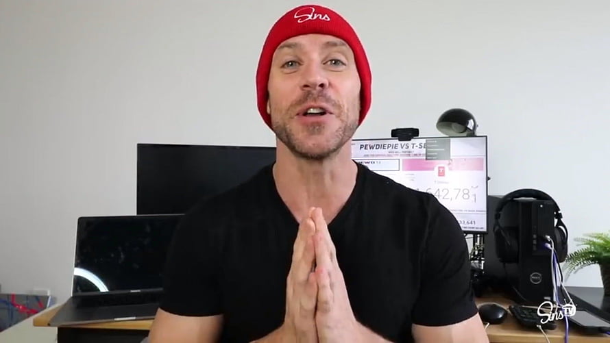 Johnny Sins in Red Beanie and Black T-Shirt at Gaming Desk Setup HD wallpaper