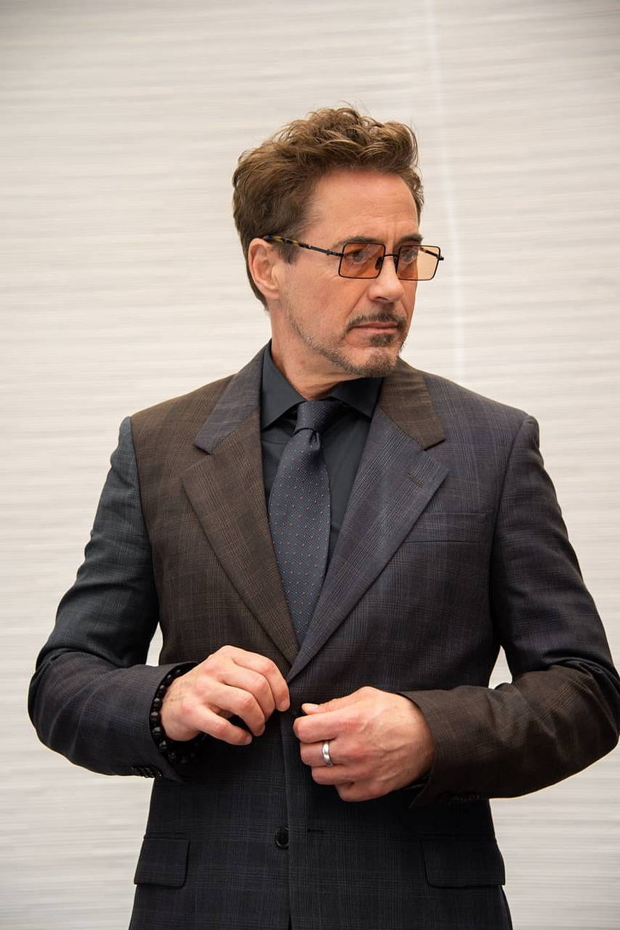 Robert Downey Jr in a tailored dark suit and amber glasses against a neutral studio backdrop HD phone wallpaper