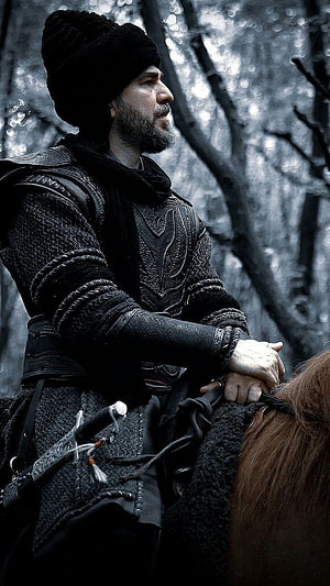 Ertugrul Ghazi in Dark Armor Riding a Horse Through a Misty Forest HD phone wallpaper