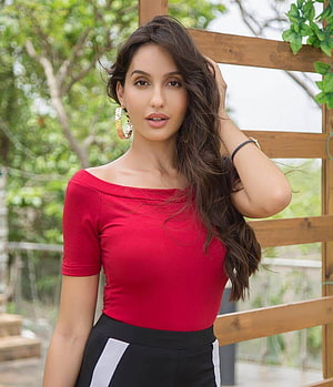 Nora Fatehi in a red off-shoulder top posing outdoors against a wooden trellis HD phone wallpaper