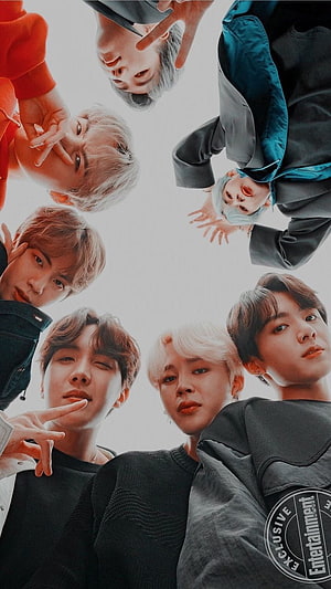 BTS members looking down in a circle formation with colorful hair and casual streetwear outfits HD phone wallpaper