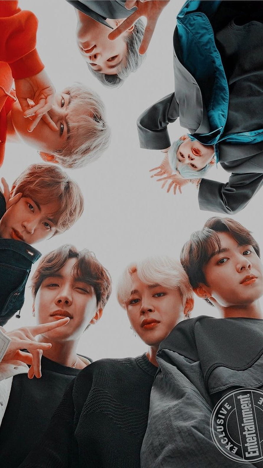 BTS members looking down in a circle formation with colorful hair and casual streetwear outfits HD phone wallpaper
