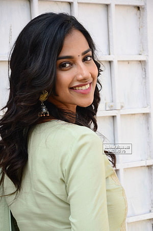 Meenakshi Chaudhary in a light green outfit with long wavy hair and traditional earrings HD phone wallpaper