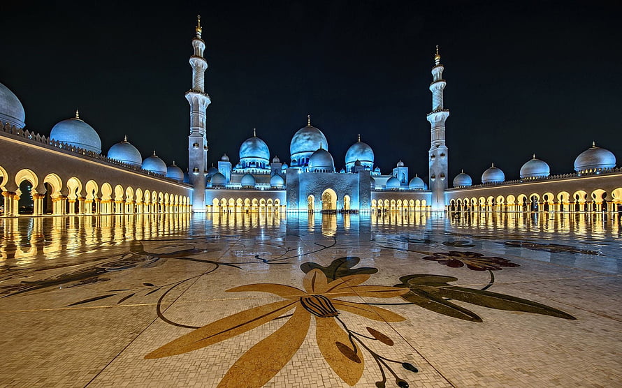 Sheikh Zayed Grand Mosque illuminated at night with blue domes and golden courtyard mosaic HD wallpaper