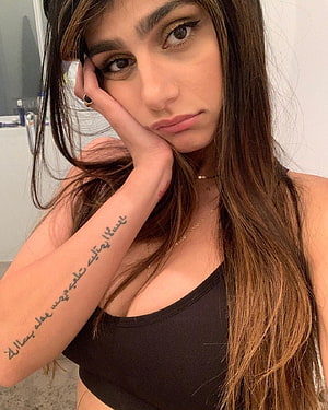 Woman with long brown hair and Arabic script tattoo on forearm posing in black top, Mia Khalifa Latest , And, mia khalifa mobile HD phone wallpaper