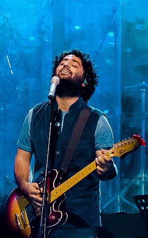 Hozier performing live on stage playing electric guitar and singing into microphone under blue lights HD phone wallpaper