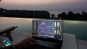 Laptop displaying financial stock market charts by an infinity pool at dusk HD wallpaper