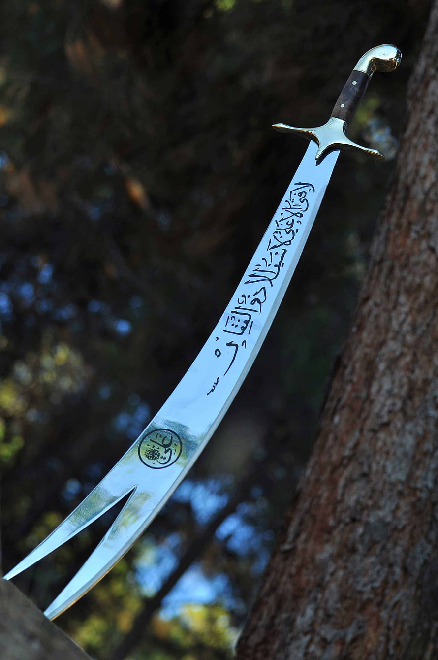 Traditional Scimitar Sword With Arabic Calligraphy Etched On Blade Resting Against Tree HD phone wallpaper