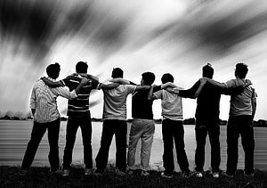 Black and white photo of seven friends standing with arms around each other by a lake HD wallpaper