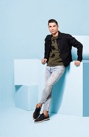 Cristiano Ronaldo in Black Jacket and Distressed Jeans Against Light Blue Studio Backdrop HD phone wallpaper