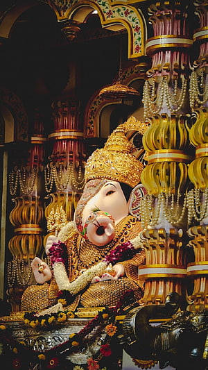 Ornate Golden Ganesha Statue in Temple with Pearl Garlands and Floral Offerings HD phone wallpaper