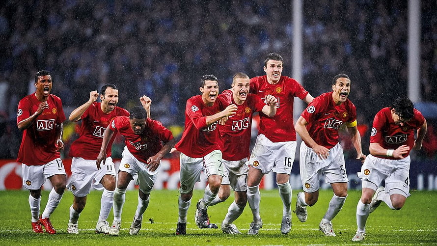 Manchester United players celebrating a goal in red AIG kits during a Champions League match HD wallpaper
