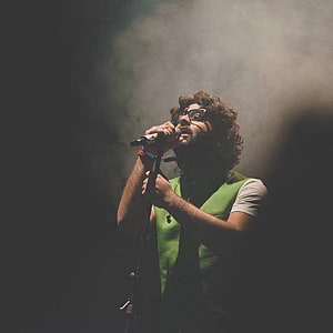 Male Singer Performing on Stage with Microphone in Smoky Atmosphere HD phone wallpaper