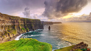 Dramatic Coastal Cliffs and Sea Stack Under Stormy Skies HD wallpaper