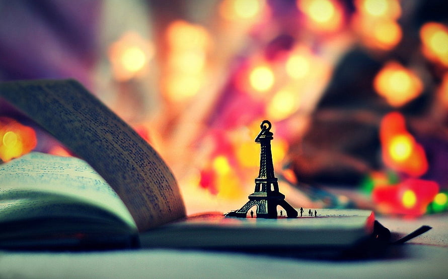 Miniature Eiffel Tower on Open Book with Warm Bokeh Lights HD wallpaper